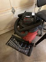 Image of Craftsman shop vacuum and set of wrenches on garage floor.