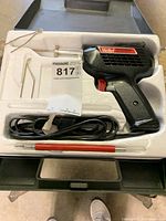 Weller soldering gun in white foam holder with soldering accessories including Allen wrenches and small red tool.