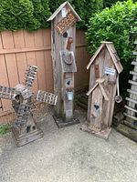 Group photo of three wooden garden decorations: a windmill, and two bird houses with rustic design and metal accents.
