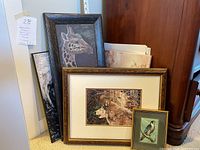 Three framed artworks grouped together: a giraffe portrait, a wolf pack print, and a smaller bird image.