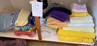 Photo of 32 assorted bath towels and washcloths in various colors stacked on a shelf.