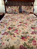 Full view of the queen size floral quilt on a bed with two floral pillow shams and pillows.