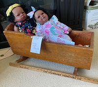 Wooden cradle containing two reborn baby dolls, showing overall lot contents.