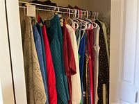 Closet rack showing an assortment of plus-size women's long dresses, blouse and skirt sets, and cover-up jackets