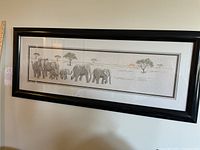 Framed needlework showing the entire elephant family art in black frame on wall