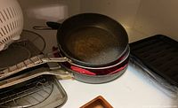Three frying pans stacked showing used condition with scratches and non-stick interior surfaces