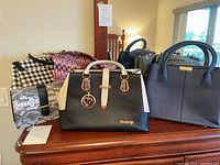 Eight handbags of various sizes and colors arranged on a surface including snakeskin-effect, black with beige panels, and structured solid bags