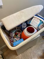 Photo of the vintage wooden laundry hamper filled with various laundry supplies and a small ironing board