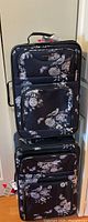 Front view of both luggage pieces stacked, showing floral pattern and zippered compartments.