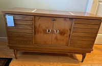 Full view of the cedar chest showing front doors, side slats, metal handles, and tapered legs.