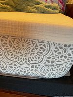 Side and corner view of queen mattress showing textured organic cotton cover and distinctive woven pattern on mattress side panel.