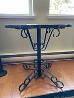 Side view of the table showing wrought iron legs with scrollwork design.