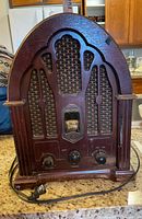 Front view of the vintage GE cathedral style radio showing dial, knobs, and wood grille