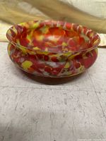Side view of the multicolor glass bowl showing its shape and chips on rim