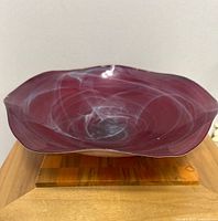Top view of red glass bowl showing white swirling patterns and smooth wavy rim.