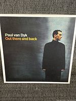 Front cover of the Paul Van Dyk album 'Out There And Back' featuring the artist in a black turtleneck looking to the side against a blurred dark blue background.