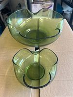Top-down view showing one large and one smaller green glass bowl with scalloped edges, placed on a cardboard box.
