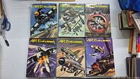 Six hardcover Air Enthusiast magazine volumes laid out on a table showing cover artwork of military aircraft in flight and combat scenarios predominantly from the 1970s.