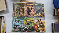 Six hardcover Air International magazines on a table with covers showing various military aircraft in flight and action scenes.