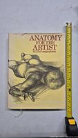 Front cover of 'Anatomy for the Artist' book featuring pencil drawing of a muscular male figure lying prone.