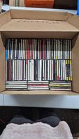 Image of multiple rows of CDs in jewel cases inside a cardboard box labeled 'FRENCH'