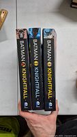 Three Batman Knightfall paperbacks, spines numbered 1, 2, 3. Volume 3 spine warped.