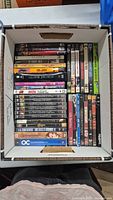 Overview of DVDs in a box showing variety of movie and TV series titles and spines.