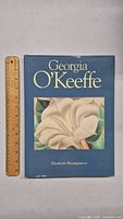 Front cover of the Georgia O'Keeffe art book showing a large white flower, with a ruler beside it for scale.
