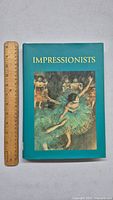 Front cover of the Impressionists art book showing a classic painting of ballerinas and the title in yellow text.