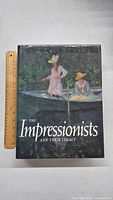 Front cover of 'The Impressionists and Their Legacy' art book with ruler for size reference