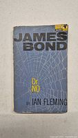 Front cover of the vintage James Bond Dr. No book showing the title and author with a spider web background.