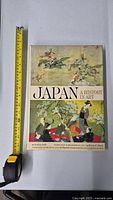 Front cover of vintage book 'Japan: A History in Art' with measuring tape showing size, featuring traditional Japanese artwork and samurai warriors.