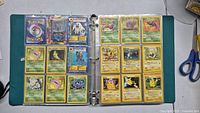 Binder open showing two pages of Pokemon cards: left page with grass-type cards, right page with electric and psychic cards