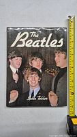 Front cover of The Beatles coffee table book showing all four members of the band in suits smiling.