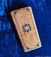 Closed etui case showing burlwood grain and decorative silver and ebony inlay on front cover