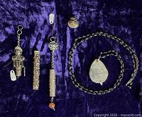 Overview of three .800 silver needle holders and silver loupe on jet bead chain displayed on purple velvet