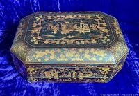 Closed view of octagonal black lacquer Cantonese sewing box with gilt painted scenes of architecture and flora, butterflies on lid and sides