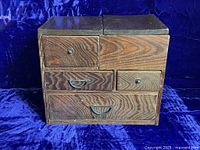 Front view of the Japanese Keyaki wood sewing box showing the drawer layout and bronze knob and bail handle hardware.