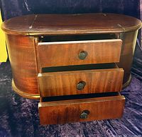 Front view showing the three drawers with metal knobs pulled open revealing interior compartments.