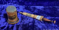 Two Mauchline sewing collectibles on a blue velvet background: cylindrical pincushion and umbrella-shaped needle case