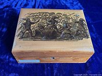 Top view of sycamore hinged sewing box showing detailed varnished etching of elves at work collecting thread spools with tools of the trade, placed on blue fabric background.