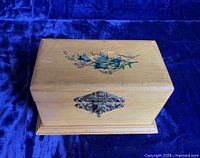 Closed view of the wooden thread box showing the front metal filigree clasp and natural wood finish