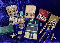 Wide view of various sewing items including multiple thread kits, wooden and Bakelite thread winders, a polished metal thread holder with pincushion, and scissors.