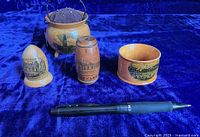 Group image showing all five Mauchline ware items on a blue velvet background next to a pen for scale