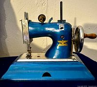Side view of royal blue miniature child's toy sewing machine showing shape and color