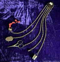 Full view of chatelaine with all five chains and tools on purple backdrop