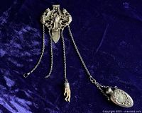 Full view of gilt-over-silver chatelaine belt clip with four chains, perfume flask, and claw pendant on dark background