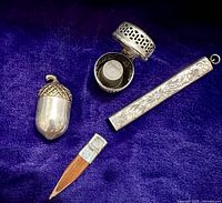 All four pieces displayed on purple velvet: acorn holder, basket chatelaine case with thimble, pencil holder and pencil