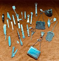 Assorted silver sewing tools and chatelaine purses laid on brown cloth