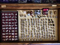 Open pine vitrine showing velvet-lined tray of sterling thimbles at left and loose thimbles arrayed on the base